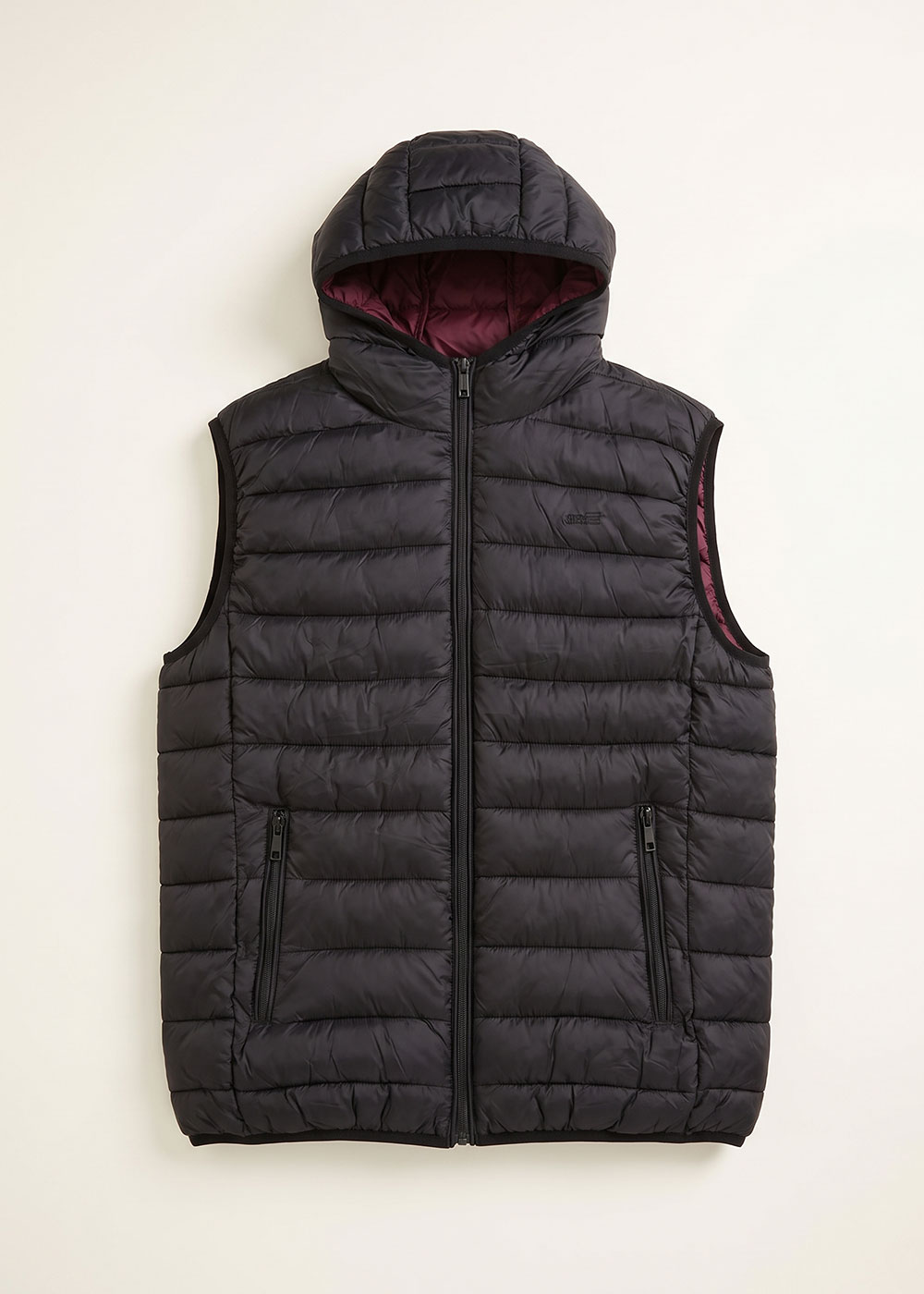 Black quilted sleeveless hooded puffer gilet with front zip, zip pockets and maroon inner lining, laid flat on cream background