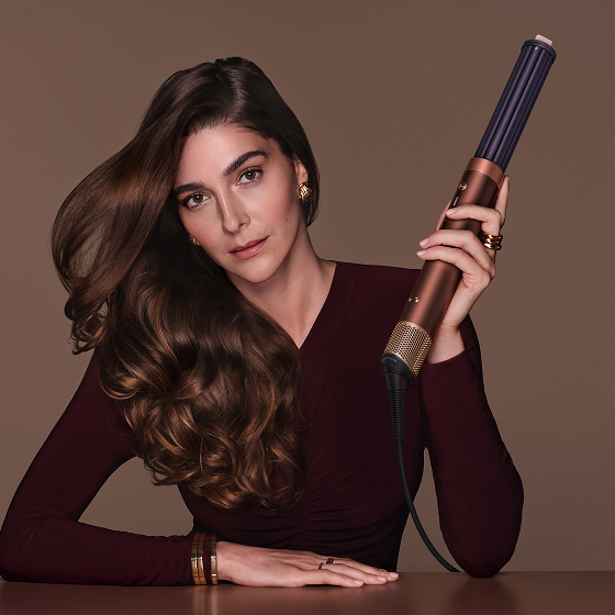 La modella tiene in mano un multi-styler e asciugacapelli Dyson Airwrap.