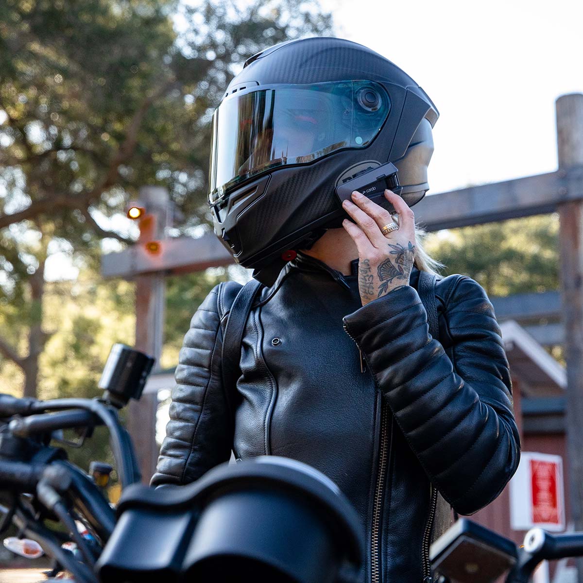Motociclista con casco integrale nero che utilizza un interfono Cardo