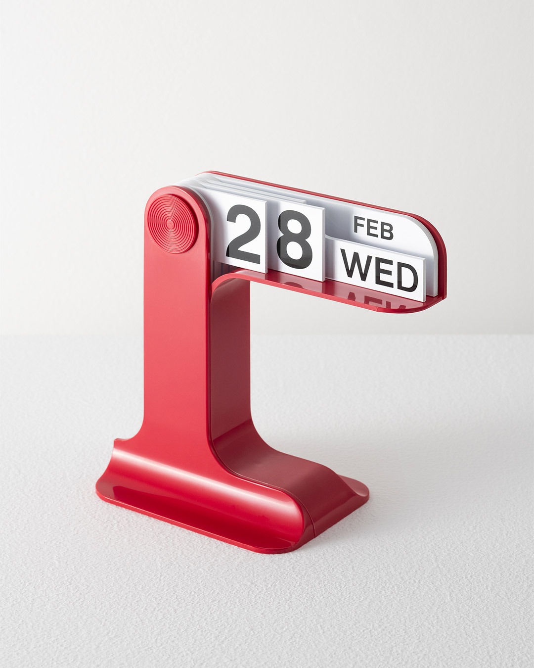 Red retro desk flip calendar displaying 28 Feb Wednesday on a white surface