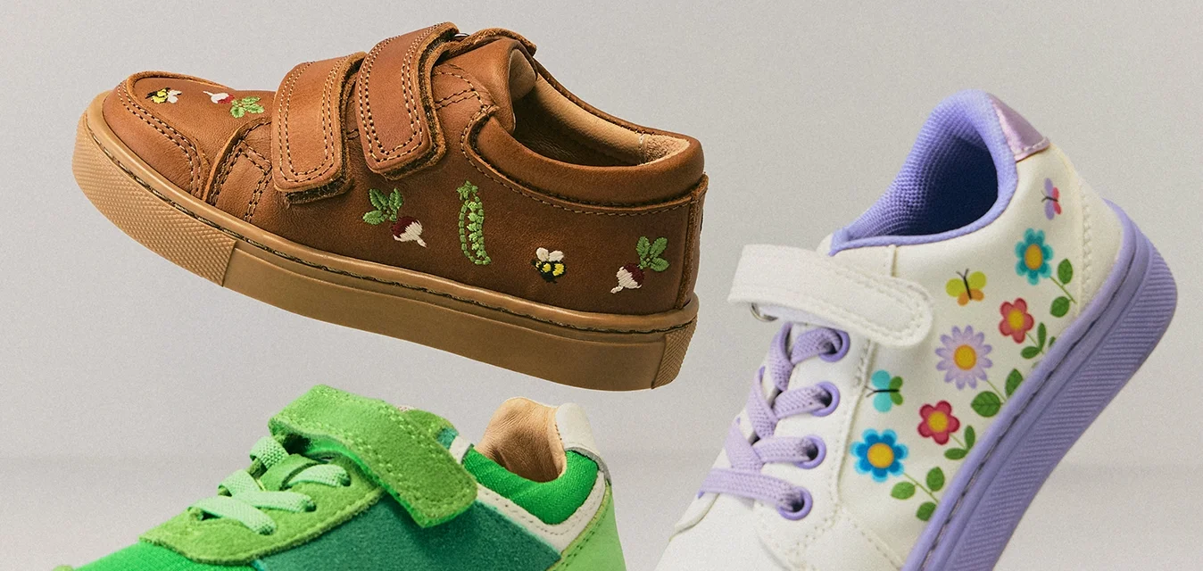 Tre paia di scarpe per bambini in aria: marroni con ricamo di ape, verdi con velcro e bianche con suola viola e motivi floreali.