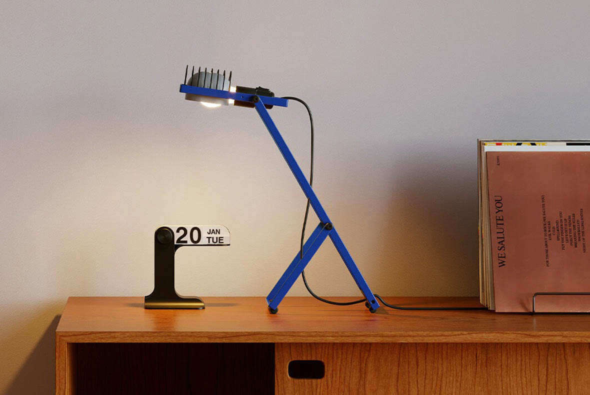Blue adjustable desk lamp illuminating a wooden sideboard with a black perpetual calendar reading “20 Jan Tue” and stacked records