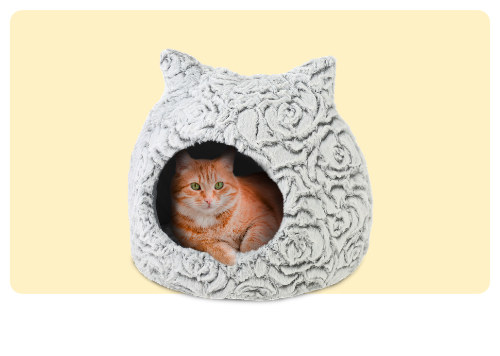 Orange tabby cat resting inside grey plush cat-shaped pet bed with floral texture on pale yellow background