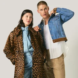 Due modelle sono in piedi una accanto all'altra; una indossa un cappotto con stampa leopardata e un completo in denim blu, l'altra indossa una giacca in denim blu, una camicia bianca e pantaloni a fantasia.