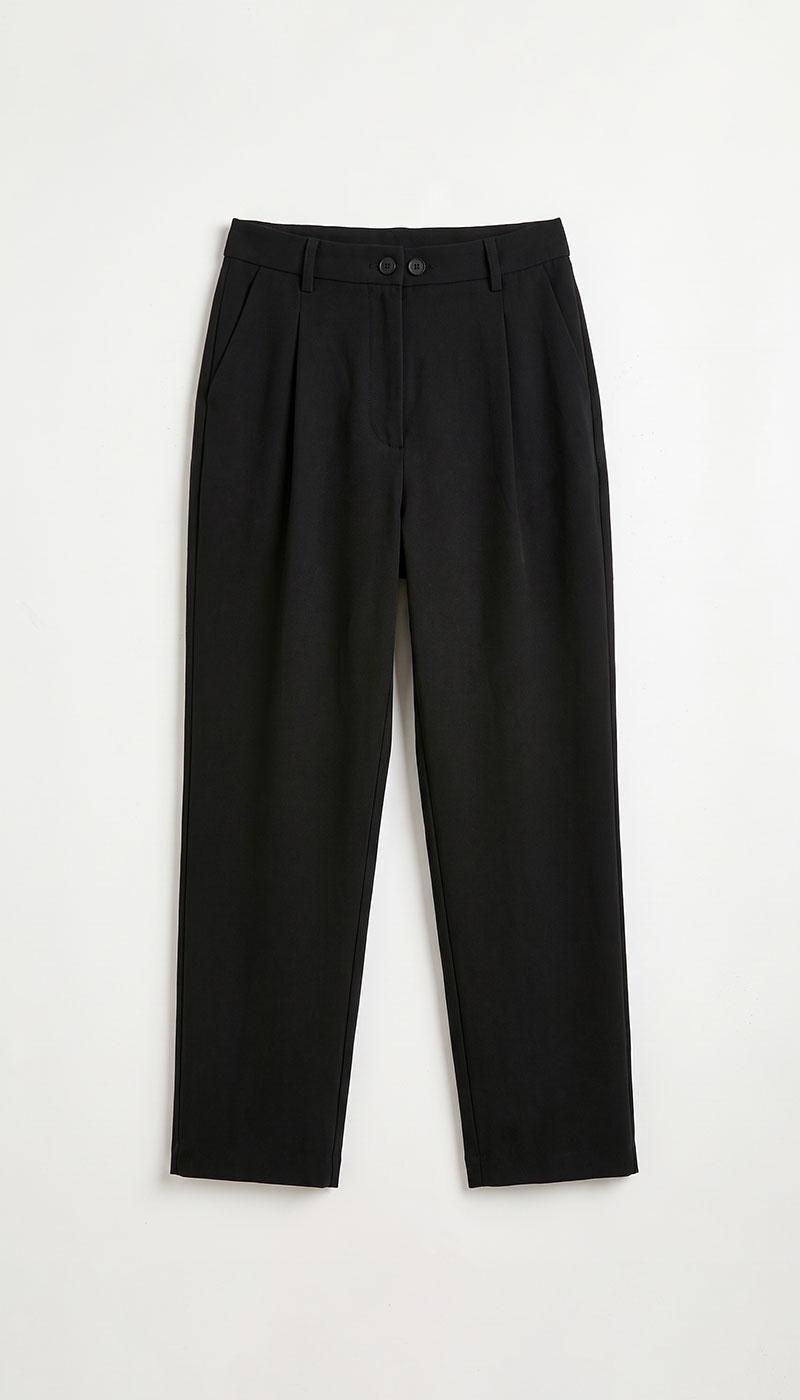 Black tailored trousers with front pleats and buttoned waistband laid flat on white background