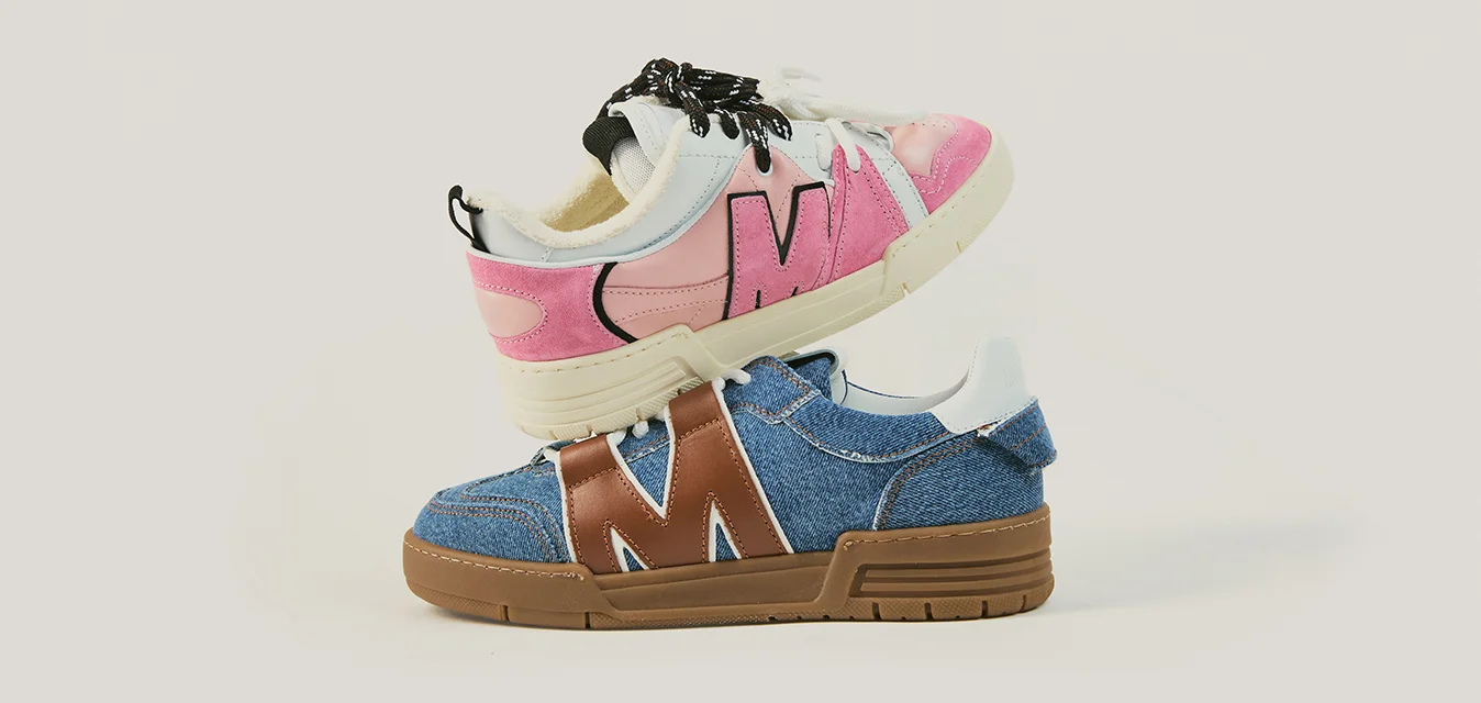 Due scarpe da ginnastica per bambini impilate, una rosa e bianca con lacci neri, una blu in denim con accenti marroni e tallone bianco, su sfondo semplice.