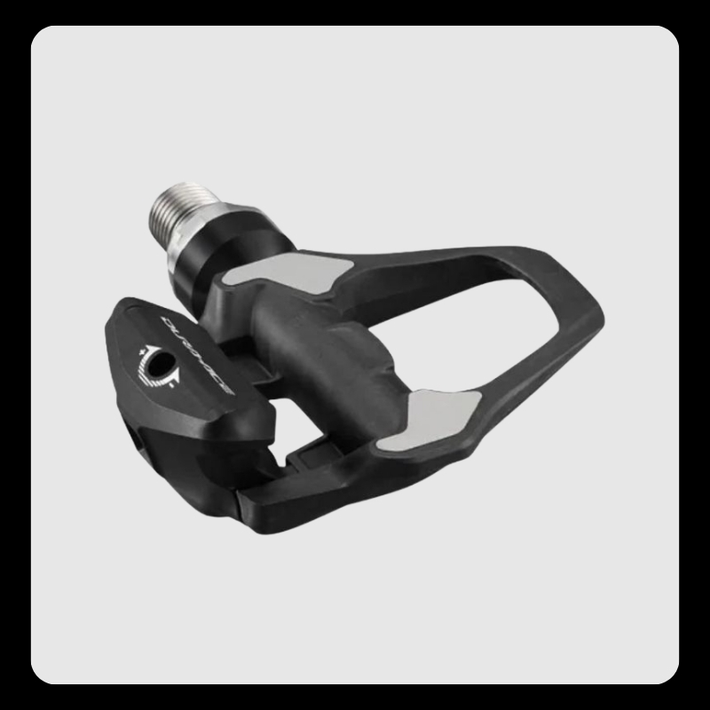 Black clipless road bike pedal with silver cleat contact areas and metal spindle on grey background