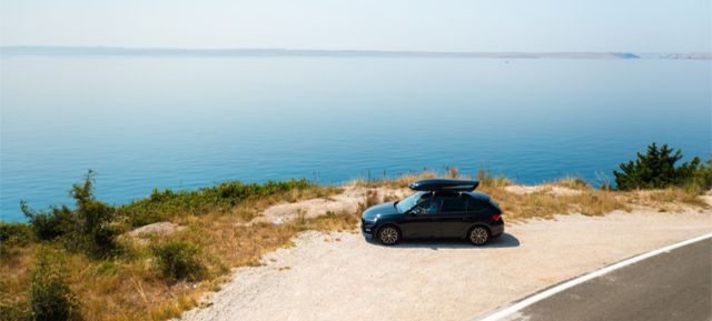 Car parked by a serene seaside view.