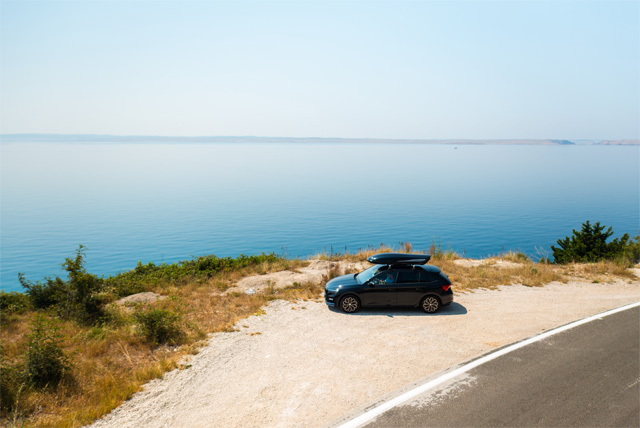 Car parked by a serene seaside view.