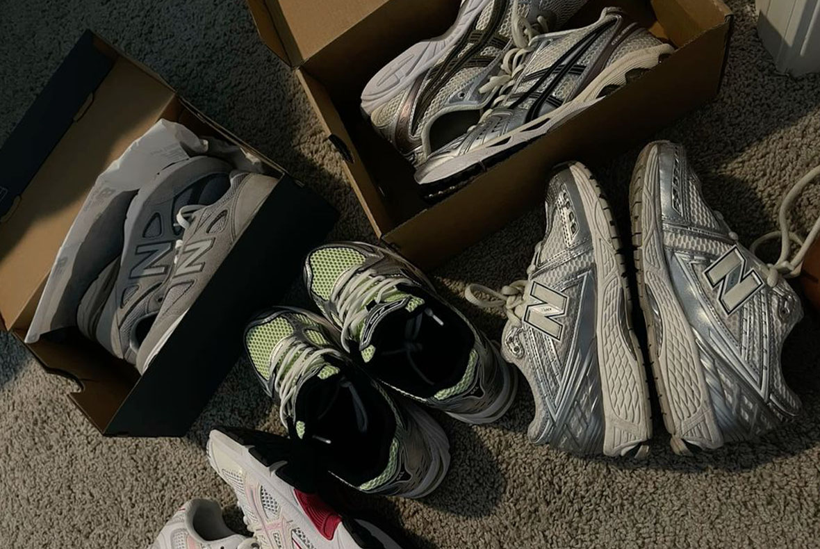 Several pairs of New Balance running shoes in grey and silver, some with neon-green accents, some in open boxes arranged on a carpet