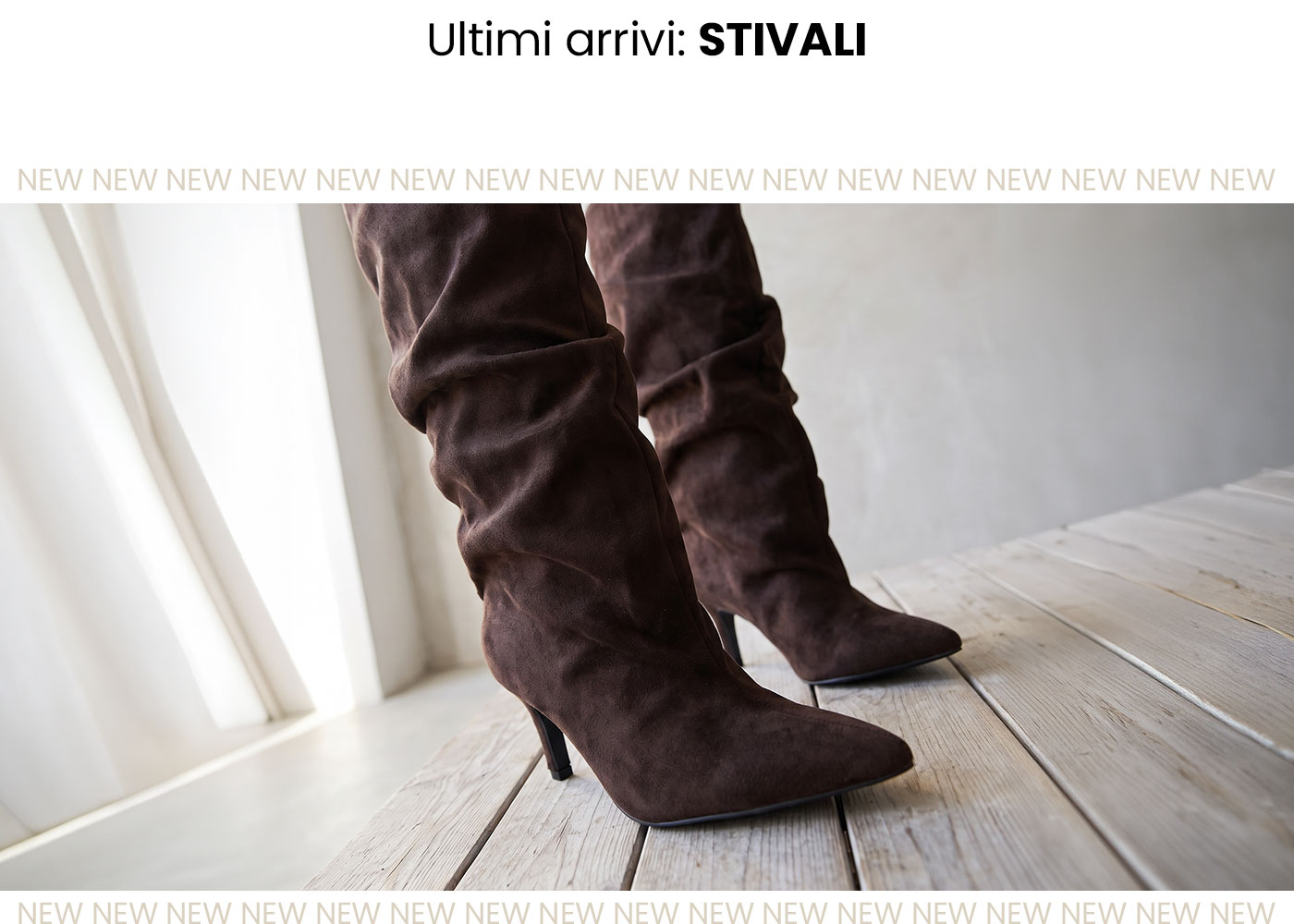 Close-up of women's brown suede knee-high slouch boots with mid heels on pale wooden floor by a sunlit window
