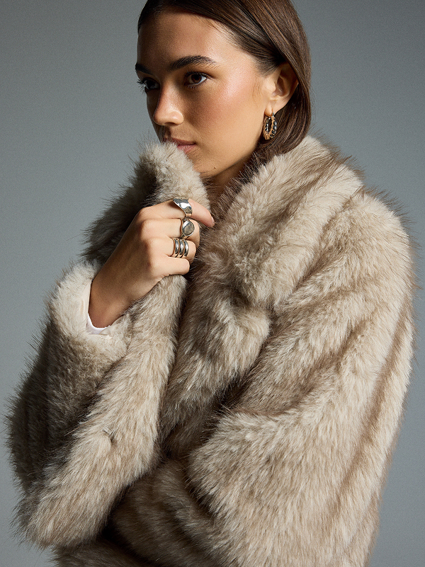 Donna con cappotto in pelliccia beige e ampio colletto.