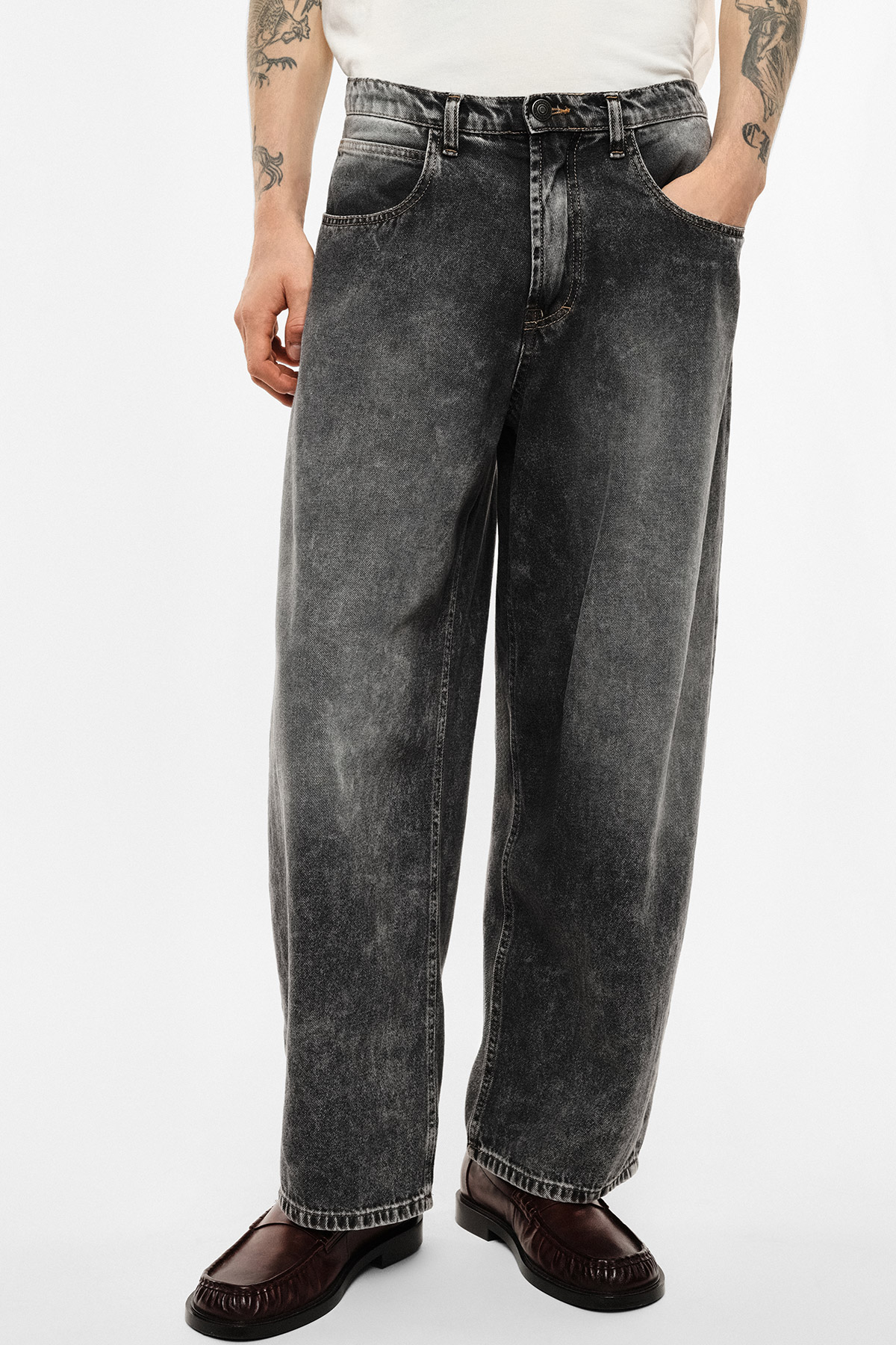 Wide-leg washed black men's jeans, mid-rise relaxed fit, model wearing a white tee and brown leather loafers