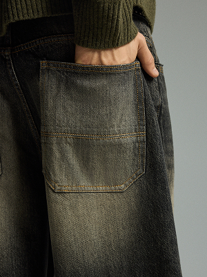 Dettaglio di jeans scuri con grande tasca posteriore e cuciture a contrasto.