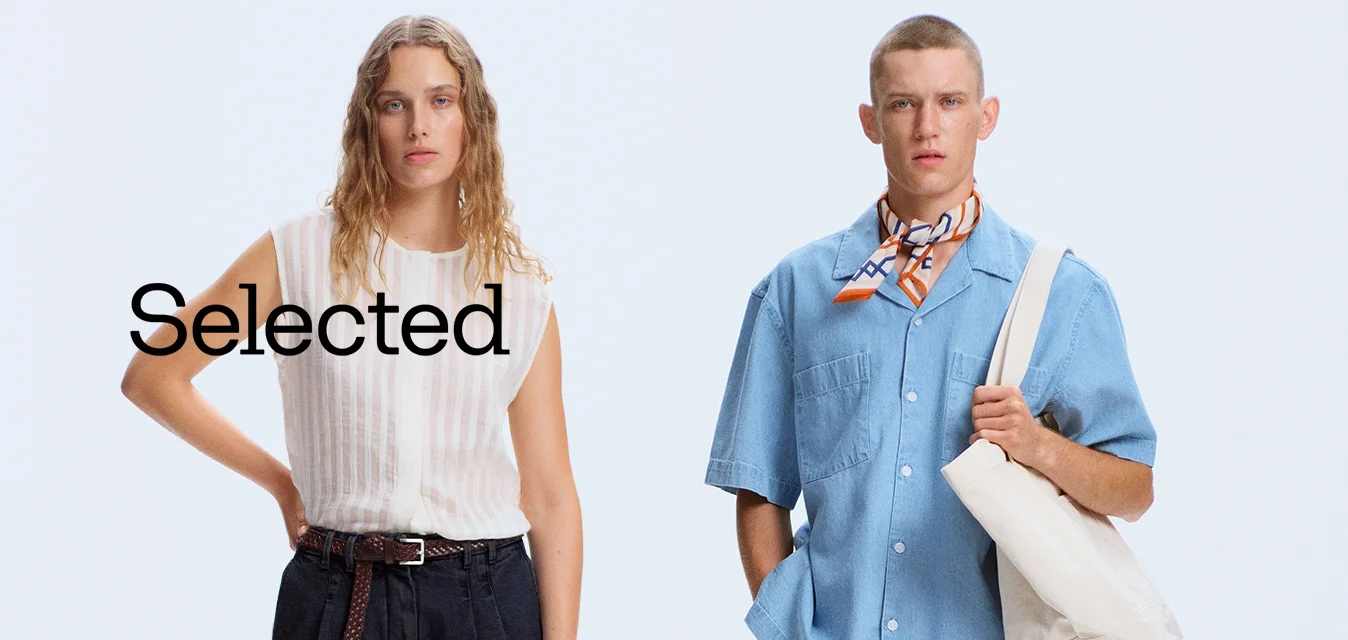 Due modelli stanno uno accanto all'altro; uno indossa una camicetta bianca senza maniche e pantaloni neri, l'altro una camicia blu a maniche corte con una sciarpa al collo e una borsa bianca.