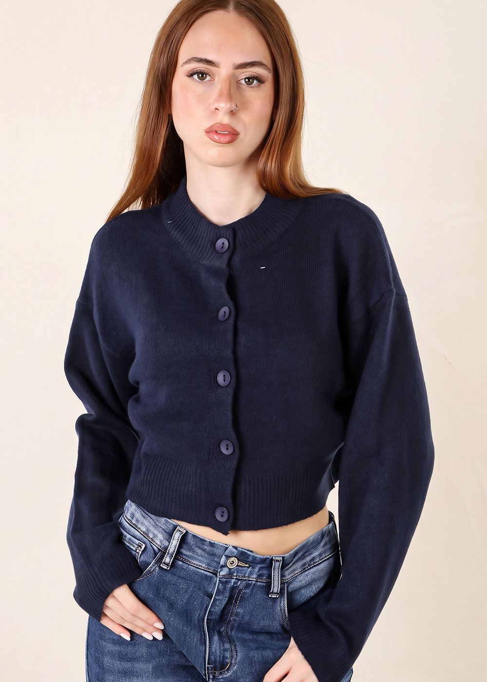 Female model wearing navy button-up cropped cardigan paired with high-waist blue jeans, posing against a neutral background