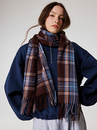 Donna con felpa blu navy, sciarpa marrone a quadri e pantaloni grigi.