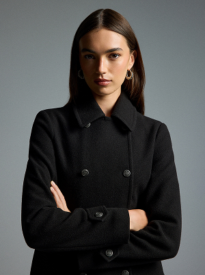 Donna con cappotto nero doppiopetto con colletto e bottoni.