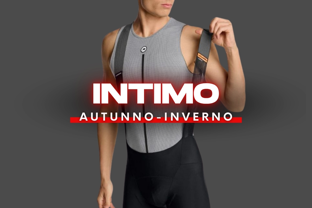 Model wearing grey thermal cycling base layer and black bib shorts holding a suspender strap with promotional text 'INTIMO AUTUNNO-INVERNO' overlay