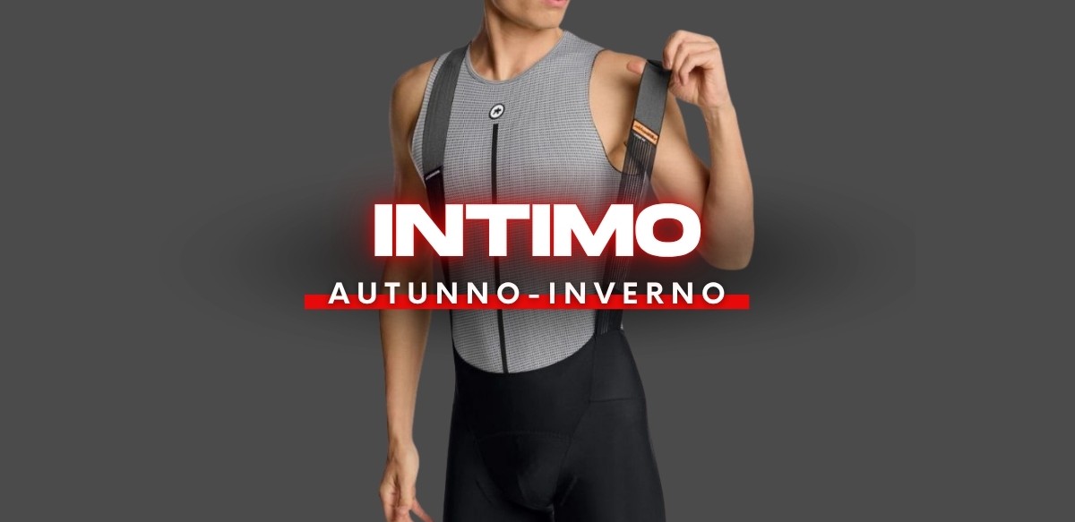 Person wearing grey sleeveless thermal base layer and black bib shorts with suspenders, seasonal 'Intimo Autunno‑Inverno' cycling kit banner