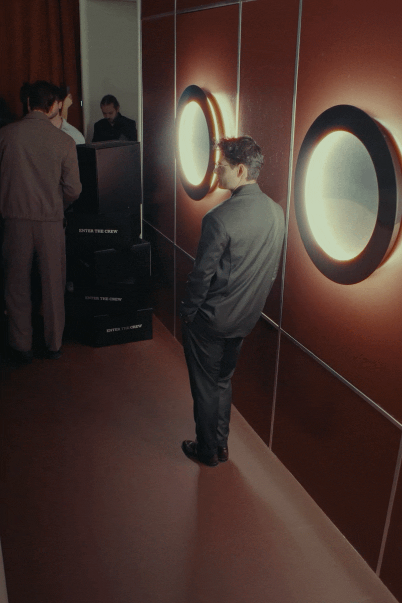 People socialising in a modern lounge with circular wall light; man stands nearby, guests seated on sofas